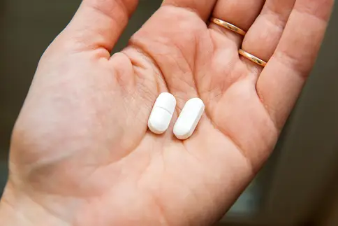photo of two ibuprofen pills in woman's hand